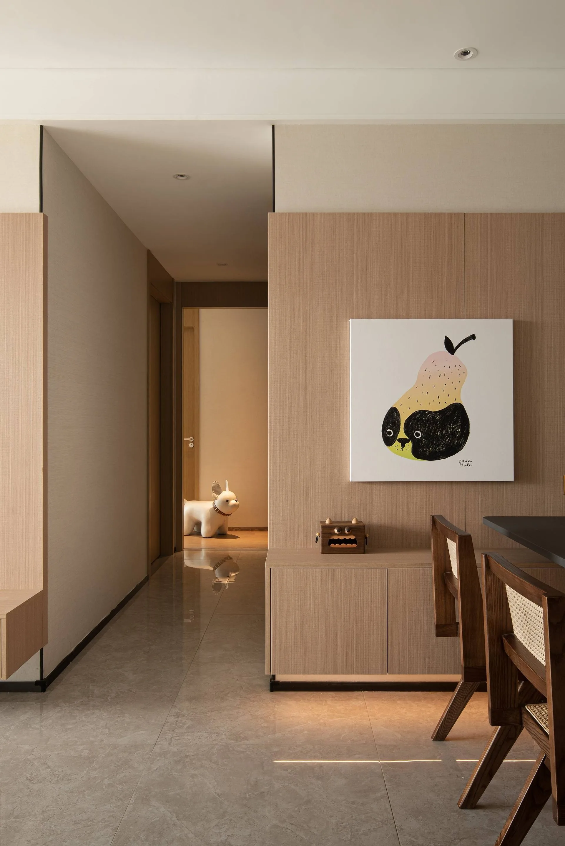 北京西岸全屋实景：浅木色柜体与同色墙板无缝衔接，嵌入式柜门配金属拉手，灰色台面与木质椅背形成层次